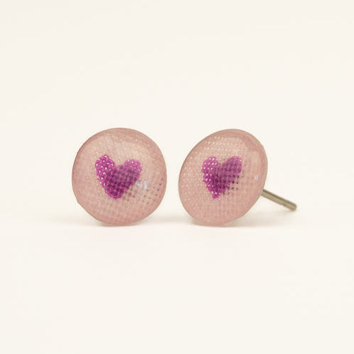 Round earrings with purple hearts on a light pink background